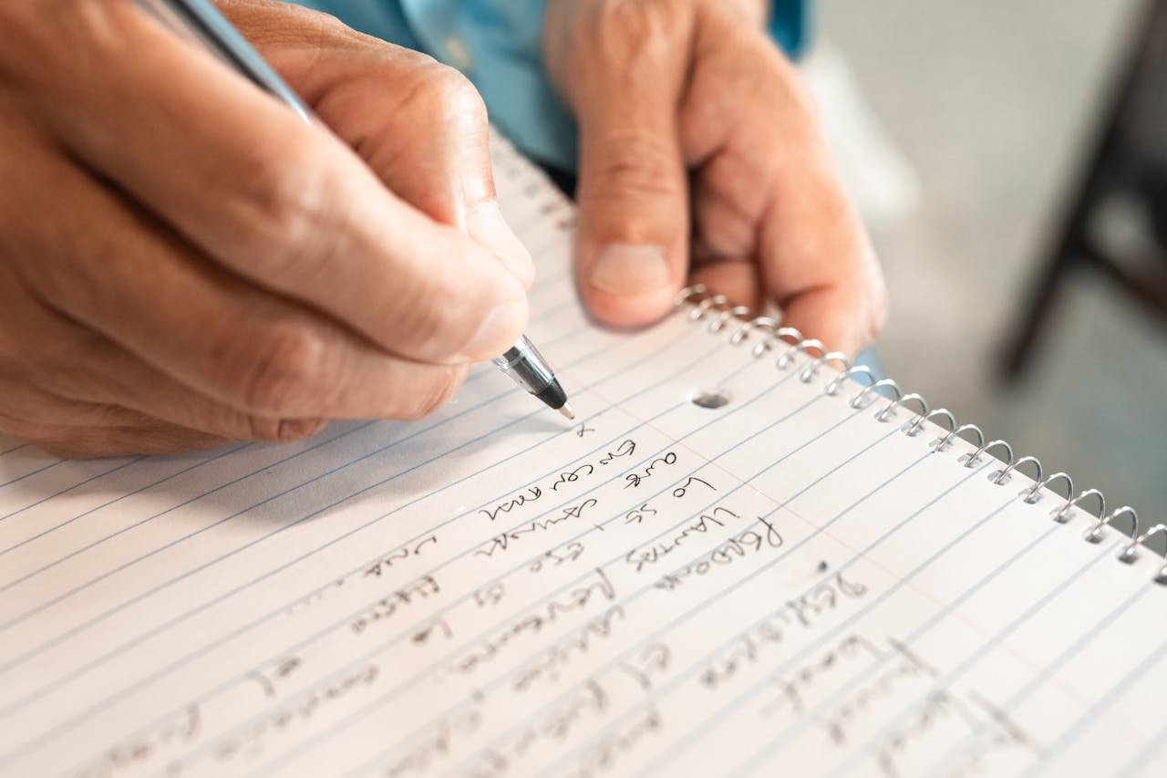 Detailed image of hands writing in a notebook, emphasizing creativity and organization.